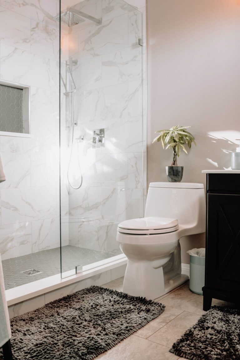 toilet in bathroom with marble shower and plant