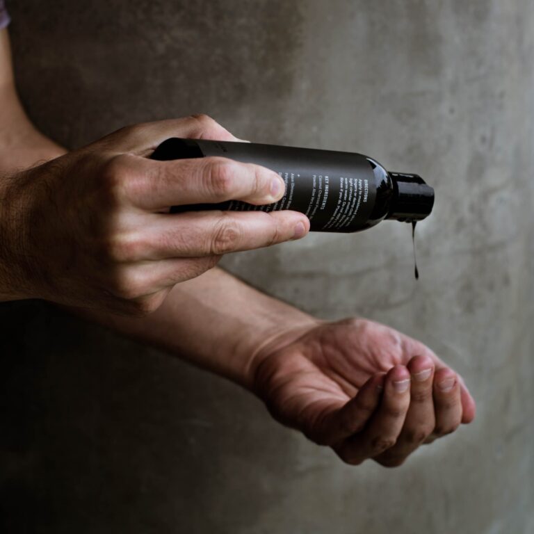 black hair relaxer being poured into hand