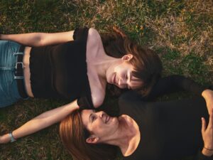 younger and older woman lying side by side in the grass