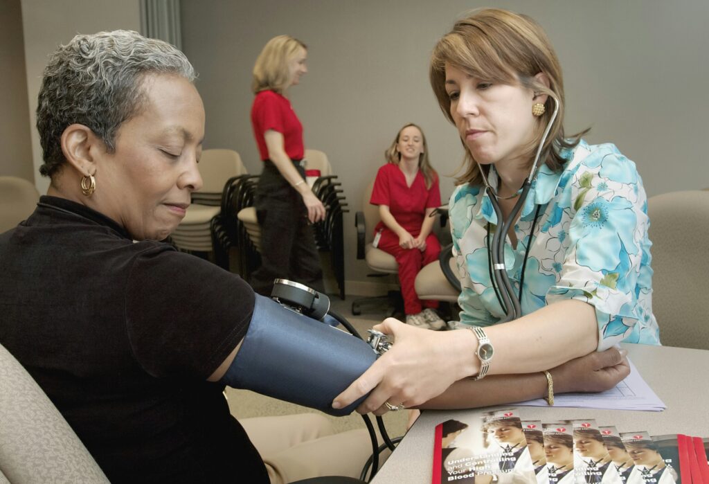 nurse measuring a black woman's blood pressure